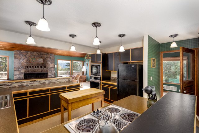 View across the kitchen toward the great room fireplace and forest windows
